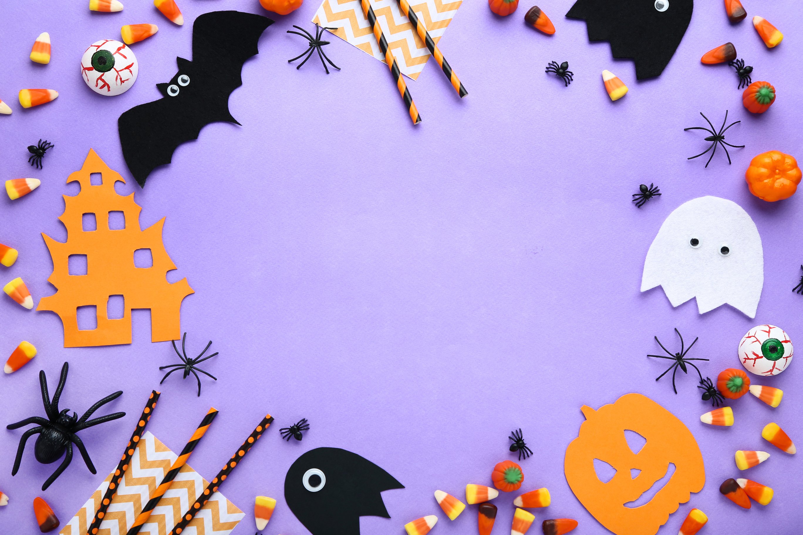 Halloween candies with paper decorations on purple background